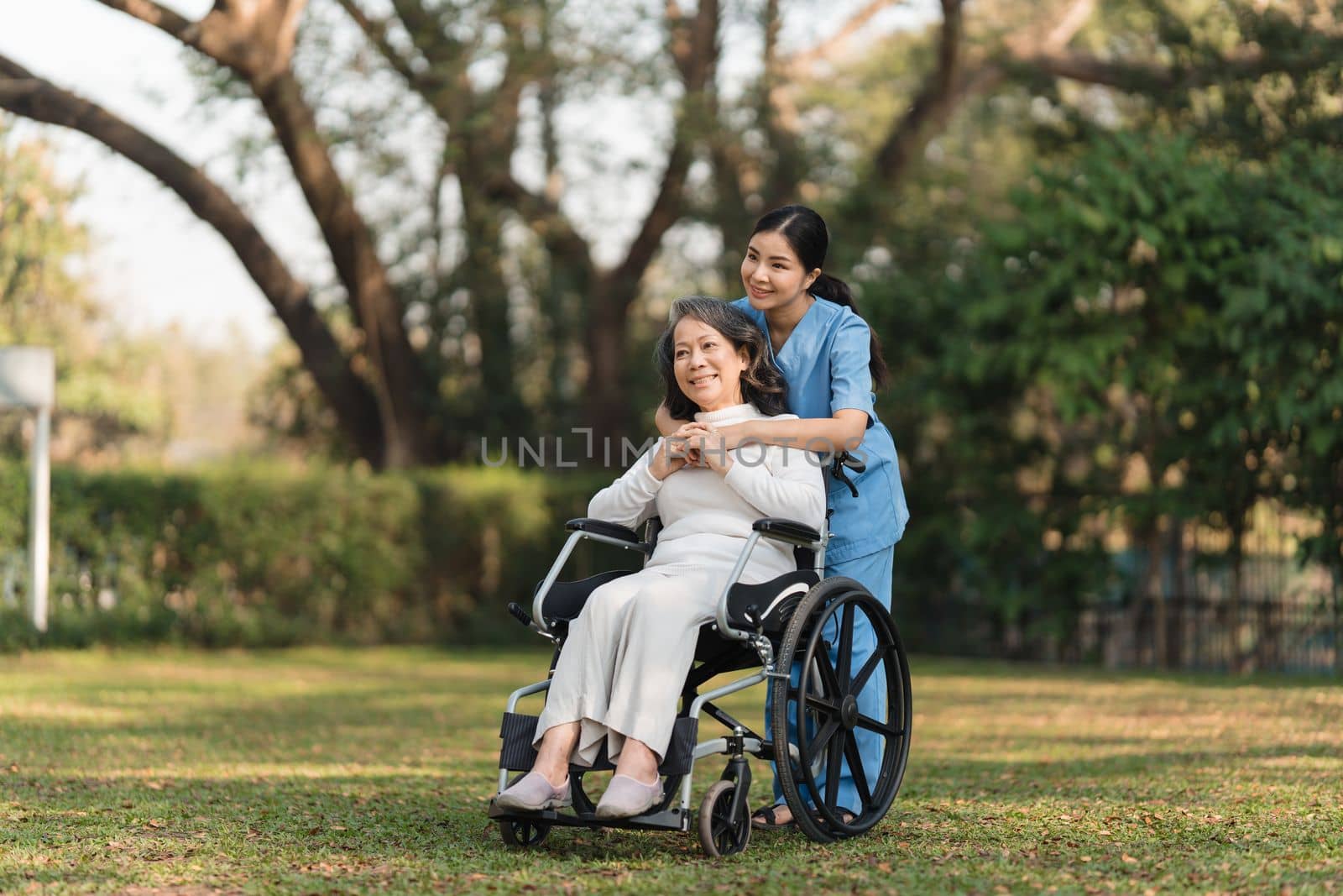 Elderly asian senior woman on wheelchair with nurse. Nursing home hospital garden concept. by itchaznong