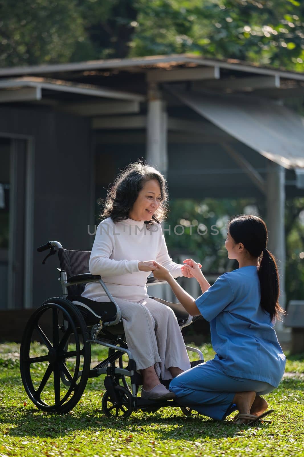 Elderly asian senior woman on wheelchair with nurse. Nursing home hospital garden concept