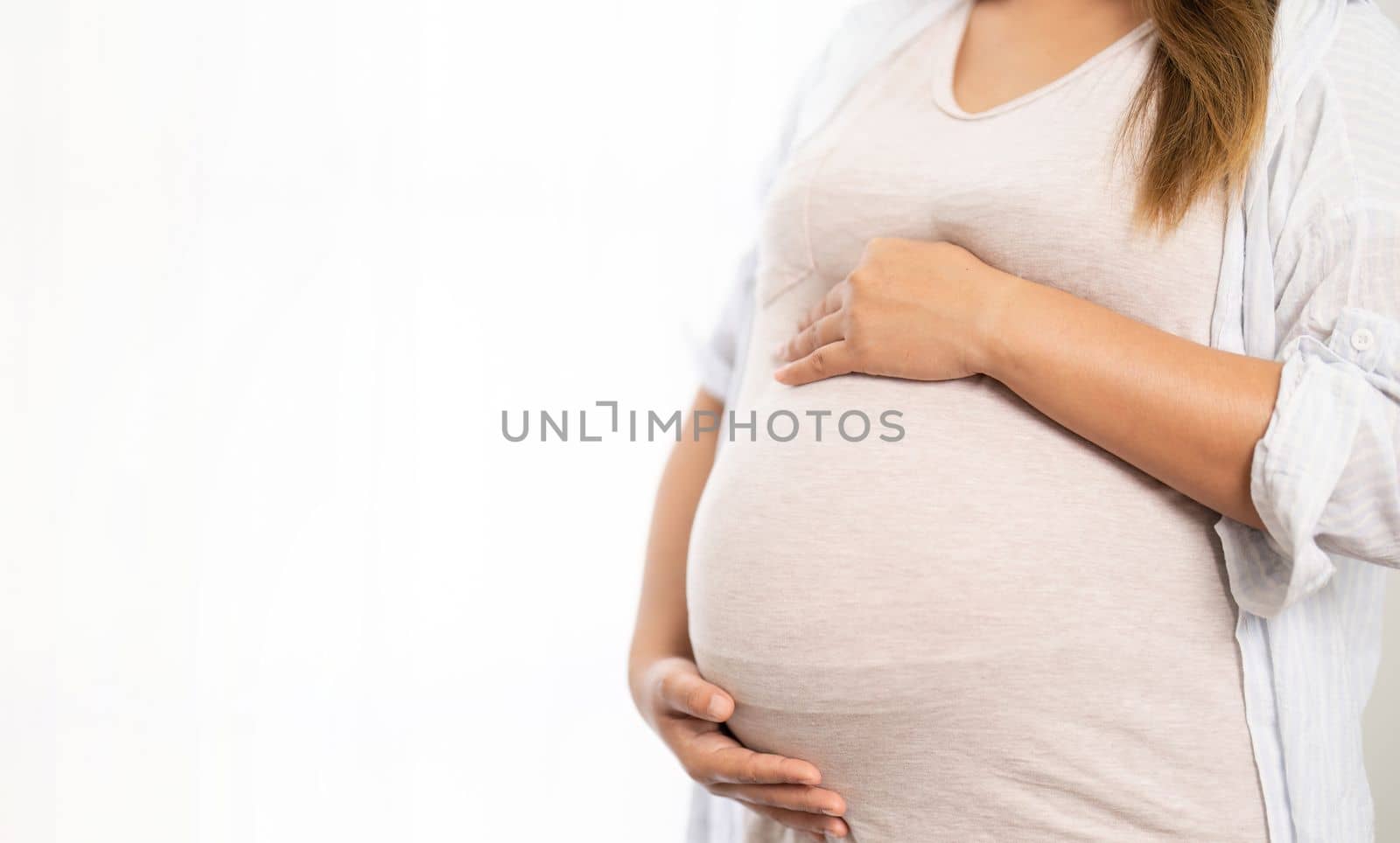 pregnant woman standing near window at home.