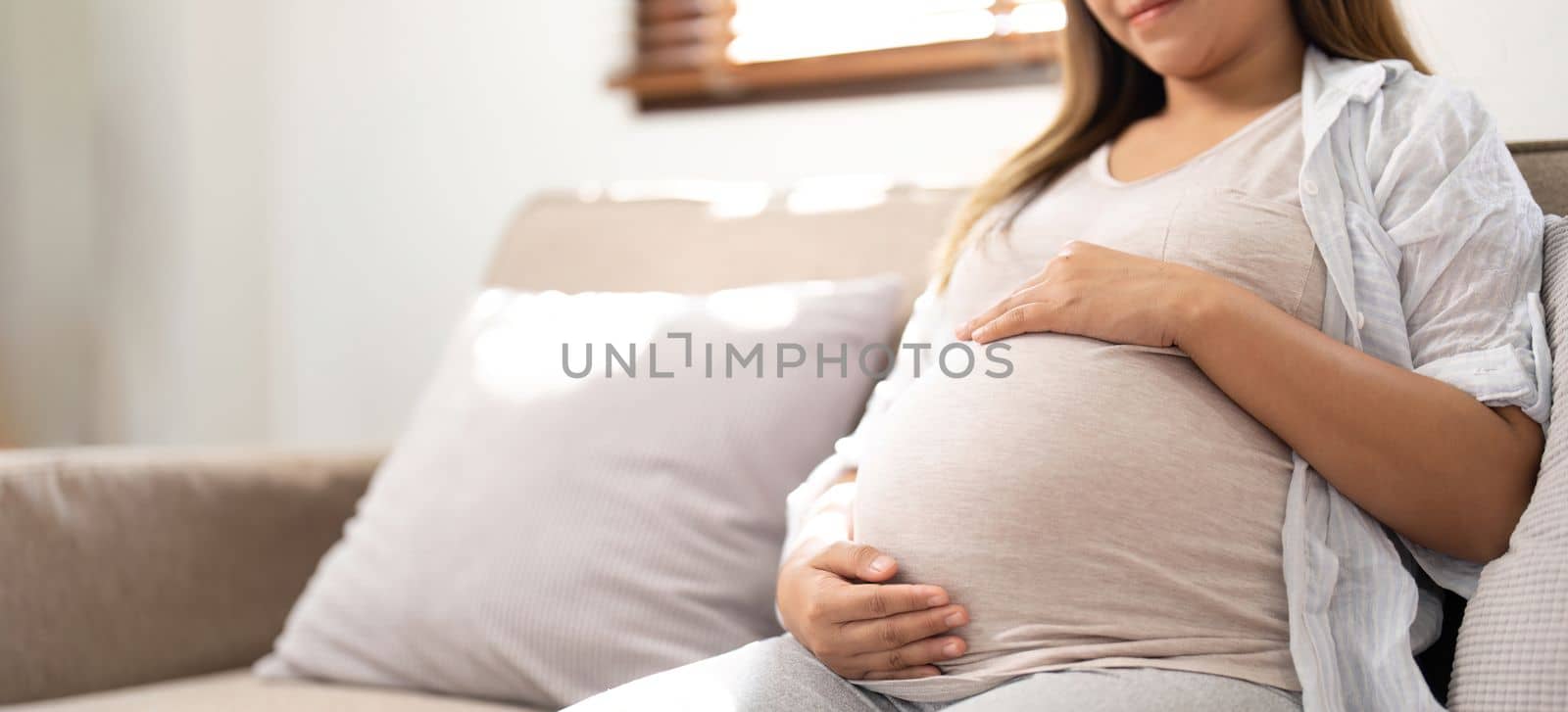 pregnancy, rest, people and expectation concept - close up of happy smiling pregnant woman in and touching her belly at home by nateemee