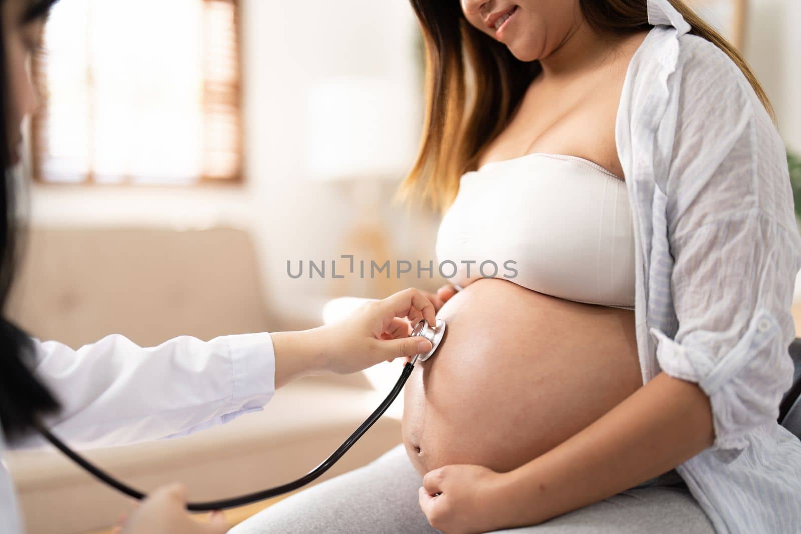 Happy Asian pregnant woman with her doctor in the examination room.