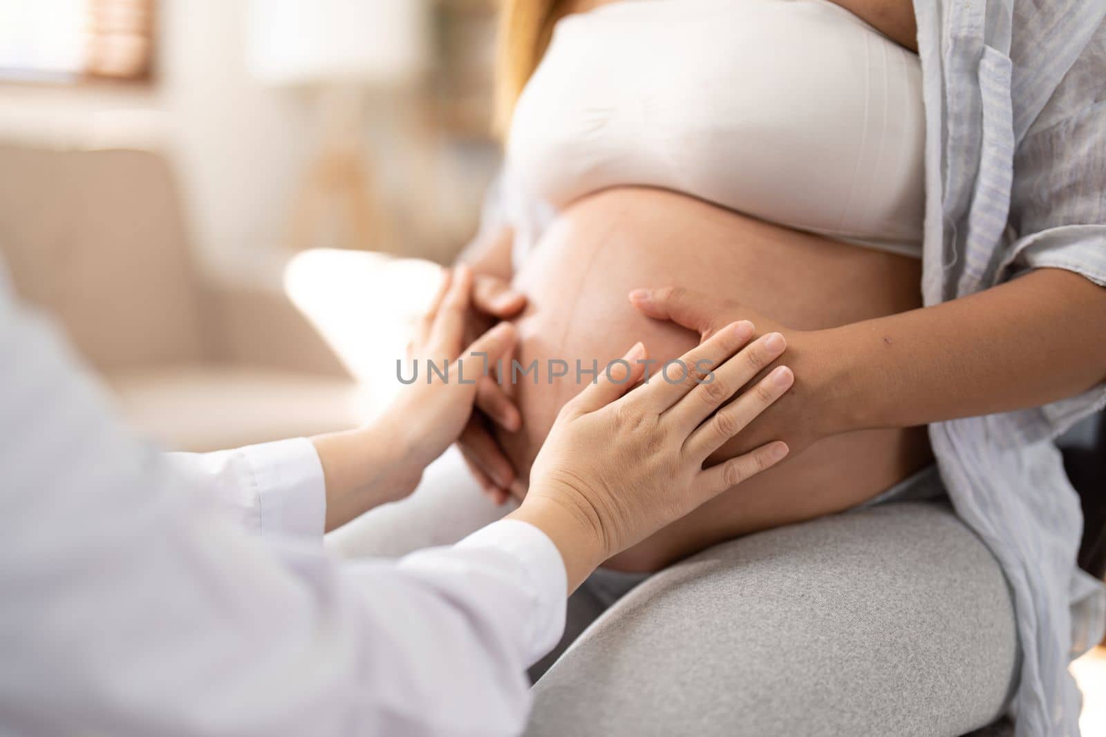 Happy Asian pregnant woman with her doctor in the examination room.
