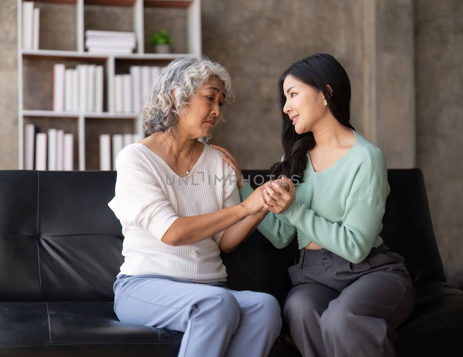 Daughter talking to sad mother holding hand comforting upset having problem.