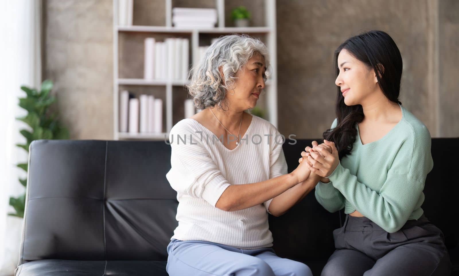 Daughter talking to sad mother holding hand comforting upset having problem.