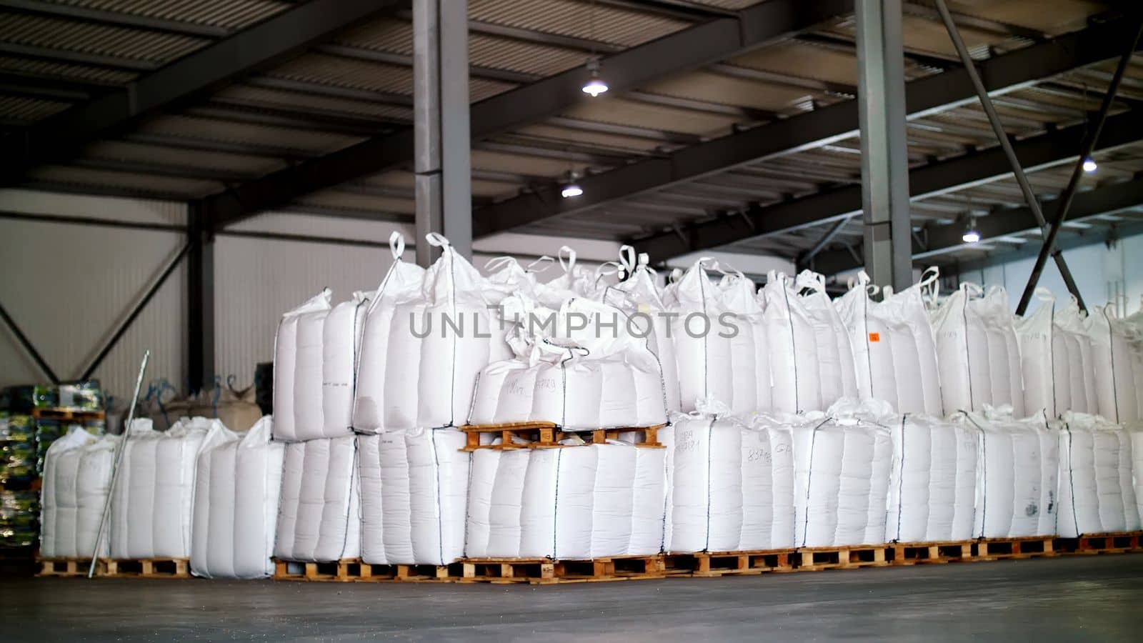 large, full bags of cereal products in stock. The bags are stacked in rows, industrial warehouse. High quality photo