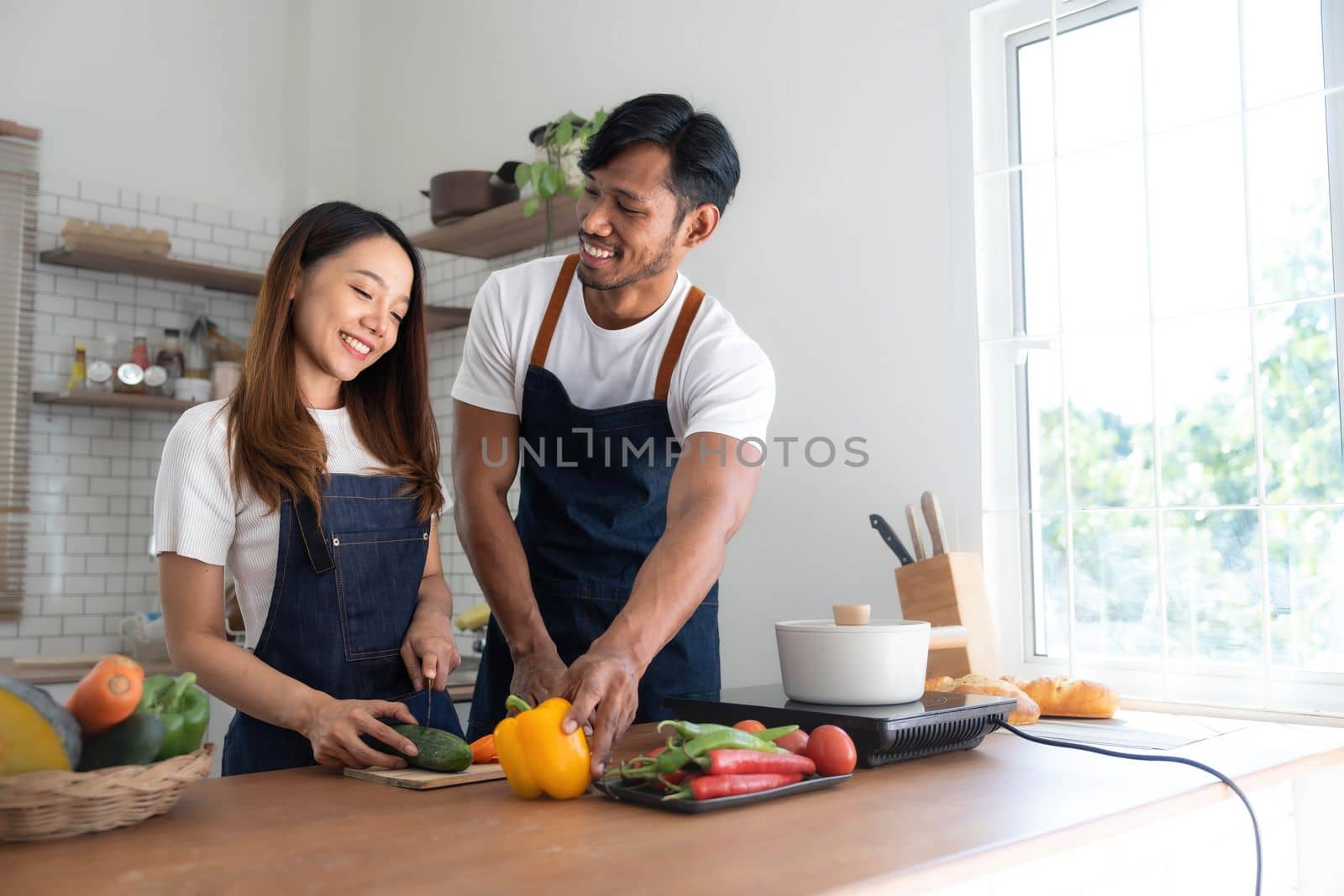 Romantic couple is cooking on kitchen. Handsome man and attractive young woman are having fun together while making salad. Healthy lifestyle concept. by wichayada