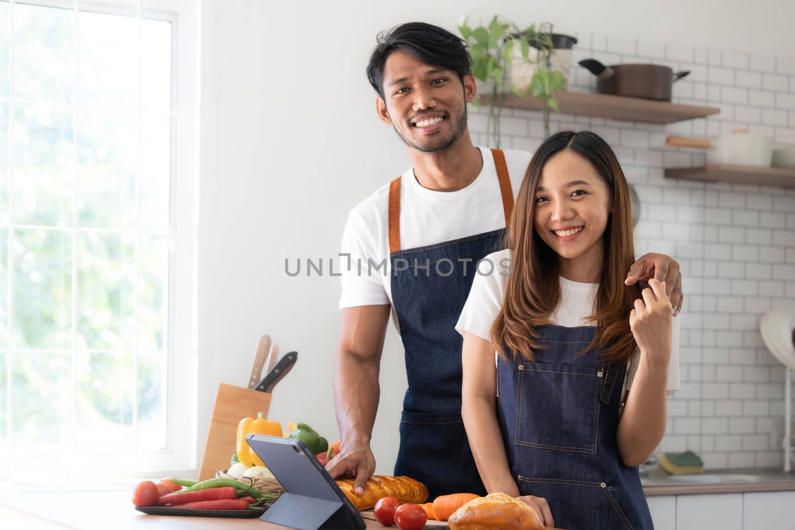 Romantic couple is cooking on kitchen. Handsome man and attractive young woman are having fun together while making salad. Healthy lifestyle concept. by wichayada