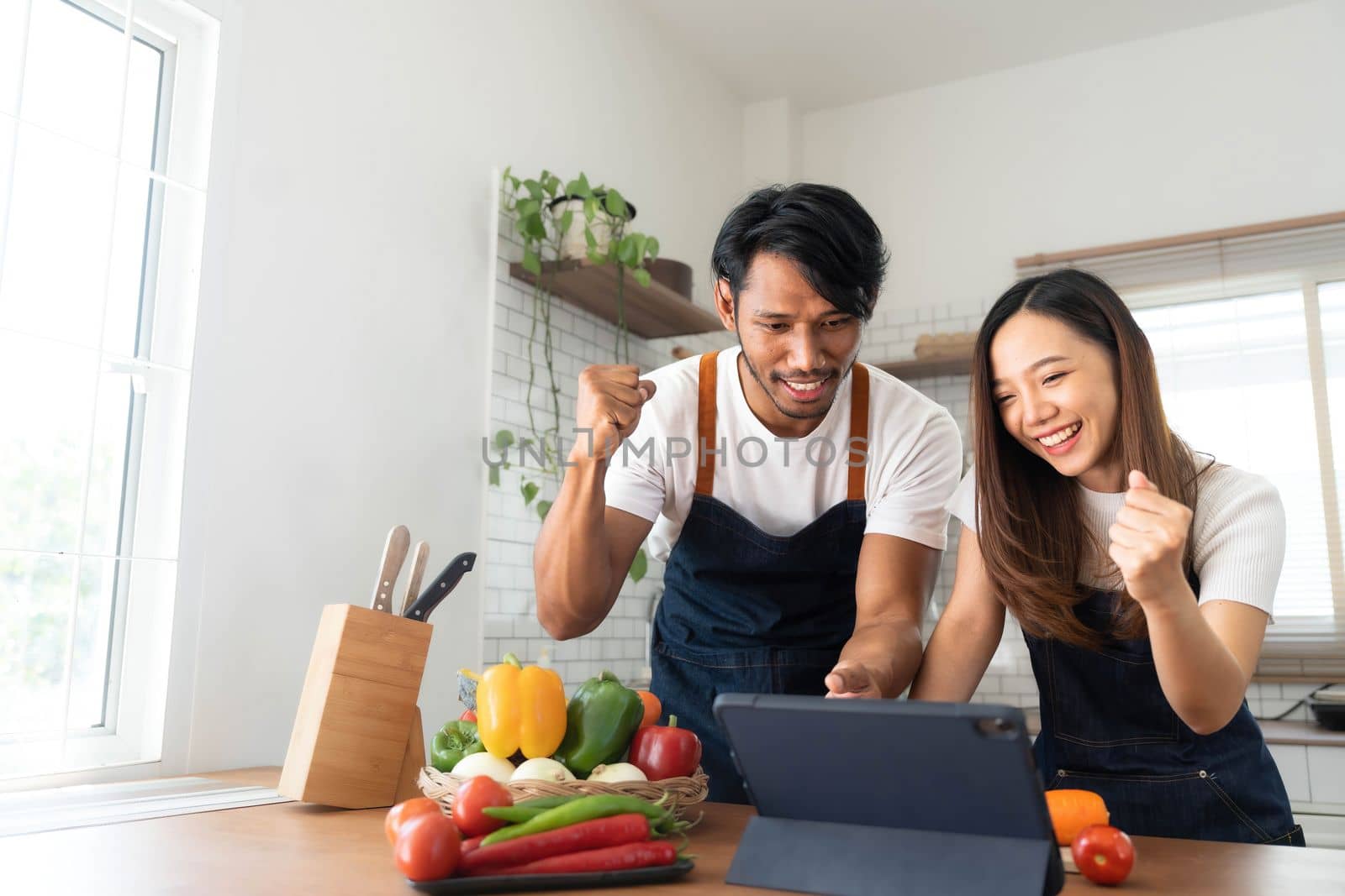 Romantic couple is cooking on kitchen. Handsome man and attractive young woman are having fun together while making salad. Healthy lifestyle concept. by wichayada