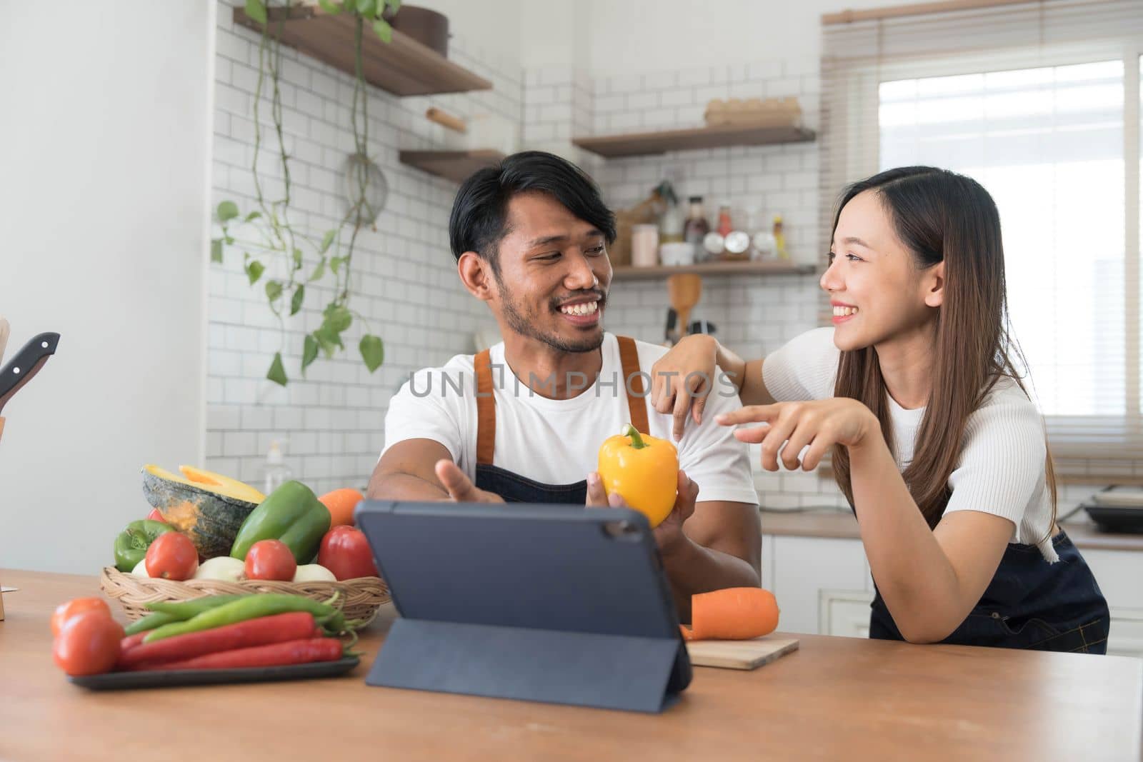 Romantic couple is cooking on kitchen. Handsome man and attractive young woman are having fun together while making salad. Healthy lifestyle concept. by wichayada