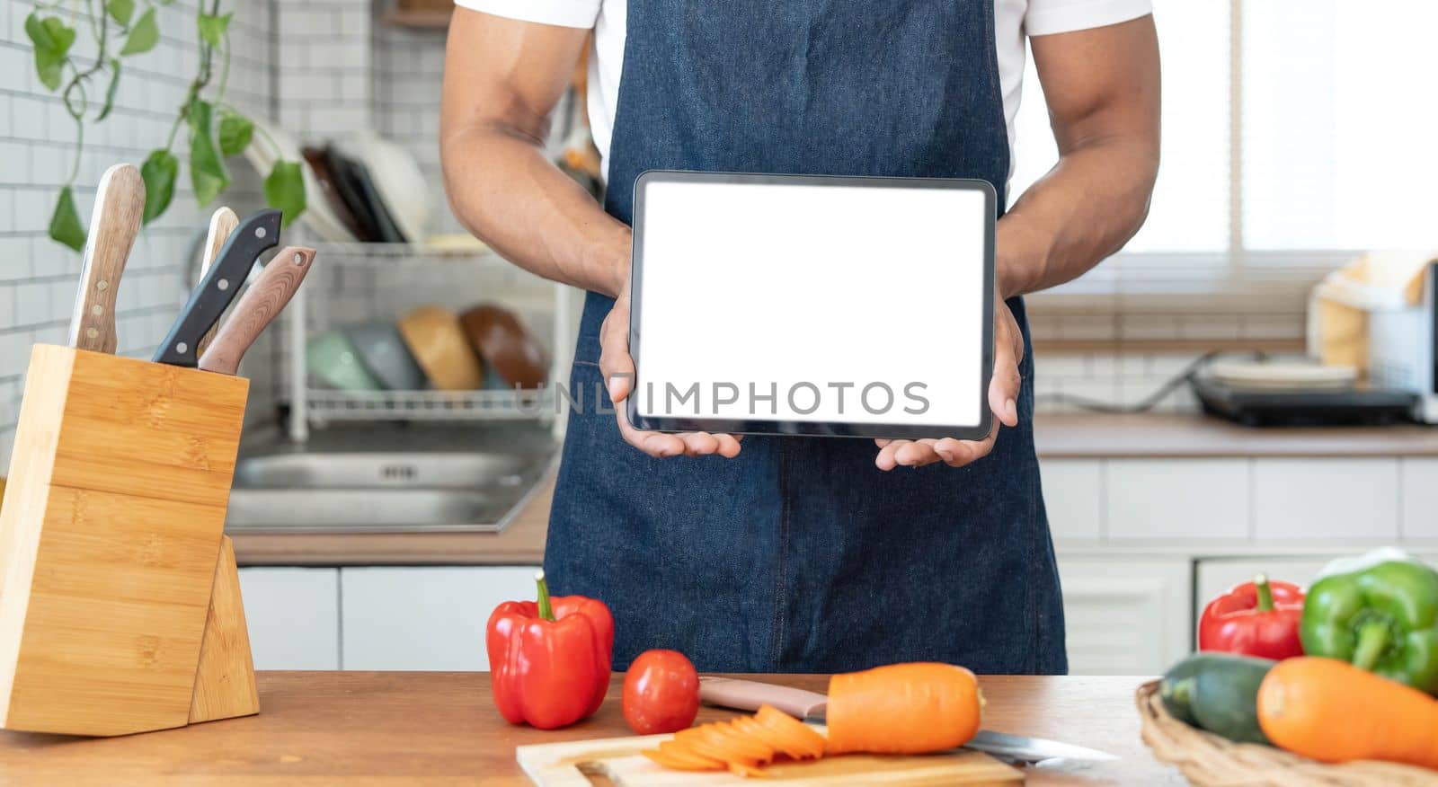 Portrait of asian man making salad and holding tablet at home. cooking food and Lifestyle moment..