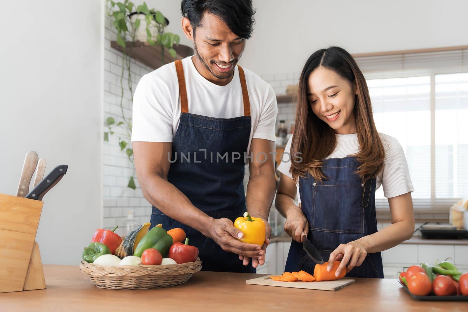 Romantic couple is cooking on kitchen. Handsome man and attractive young woman are having fun together while making salad. Healthy lifestyle concept. by wichayada