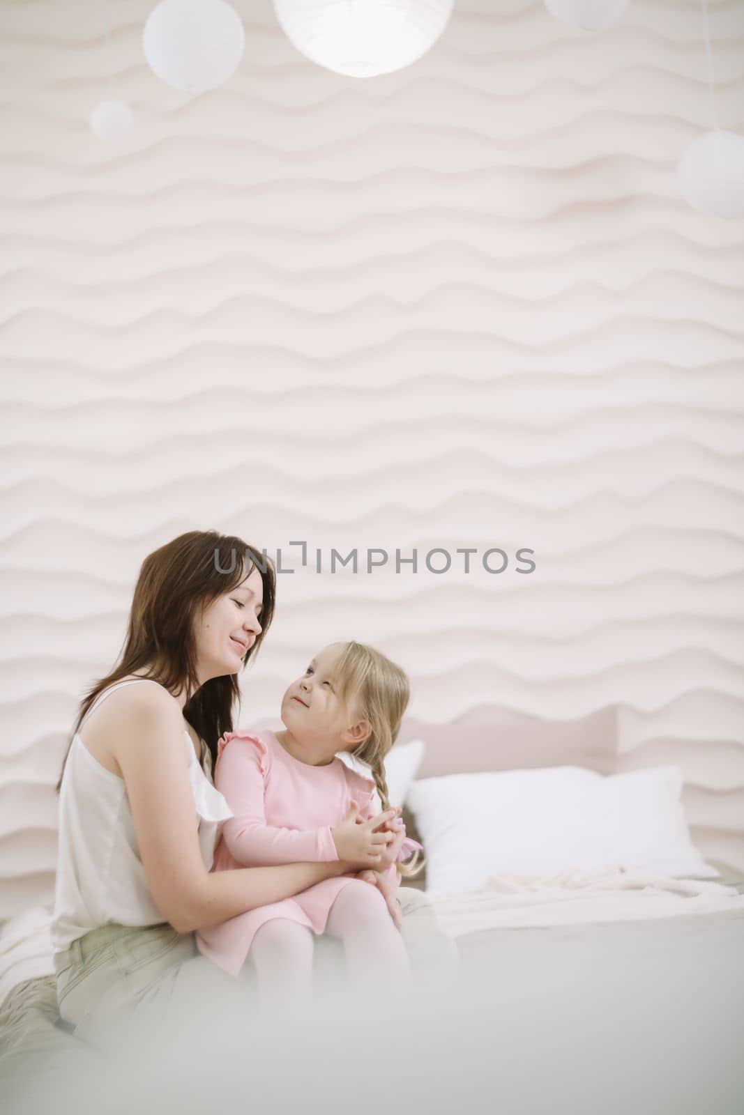 Woman in light clothes have fun with cute child baby girl 3 years old. Mommy little kid daughter on beige background studio portrait. Mother's Day love family parenthood childhood concept.