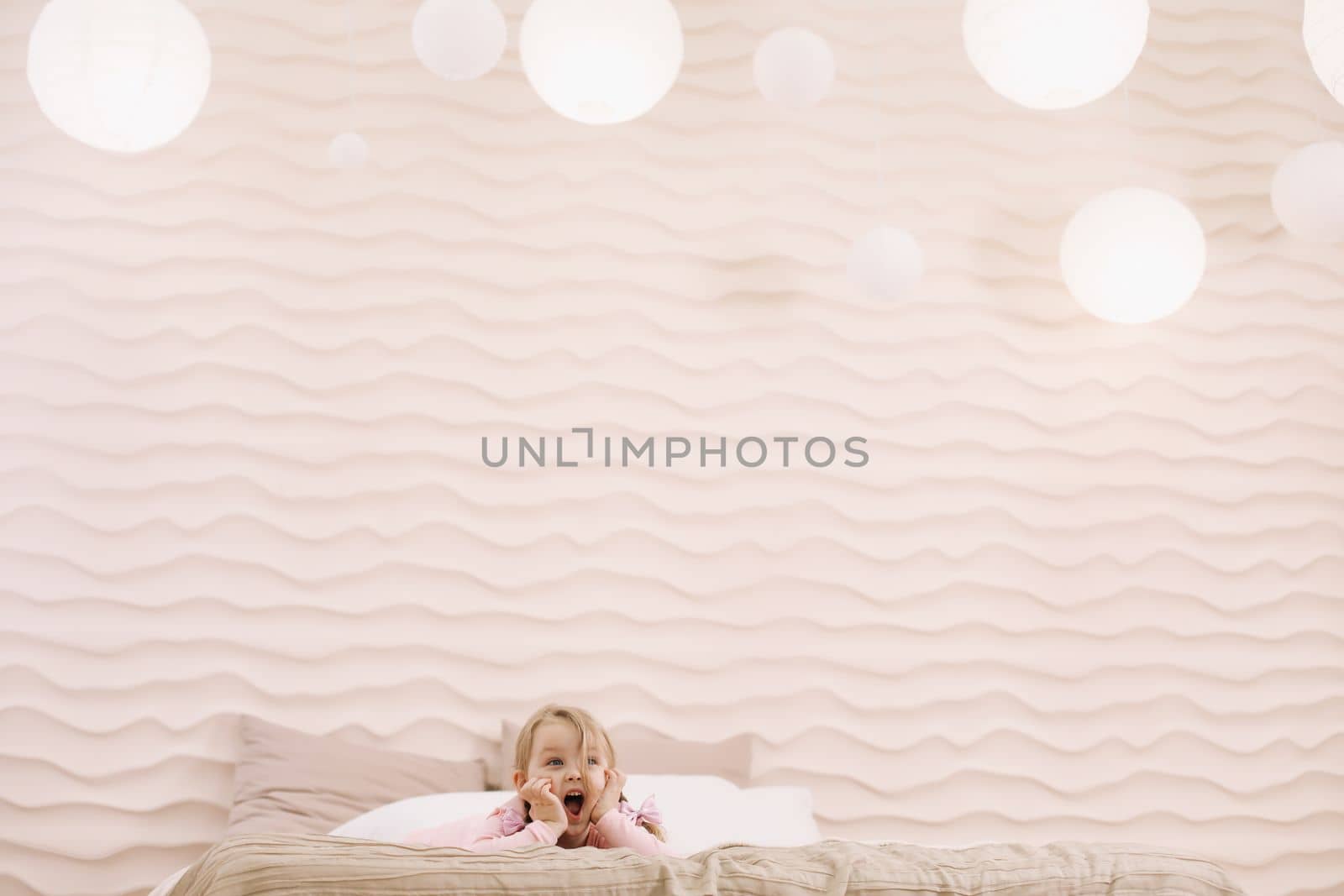 Morning of little girl in a comfortable bedroom. Happy child girl having fun and plays in bed.