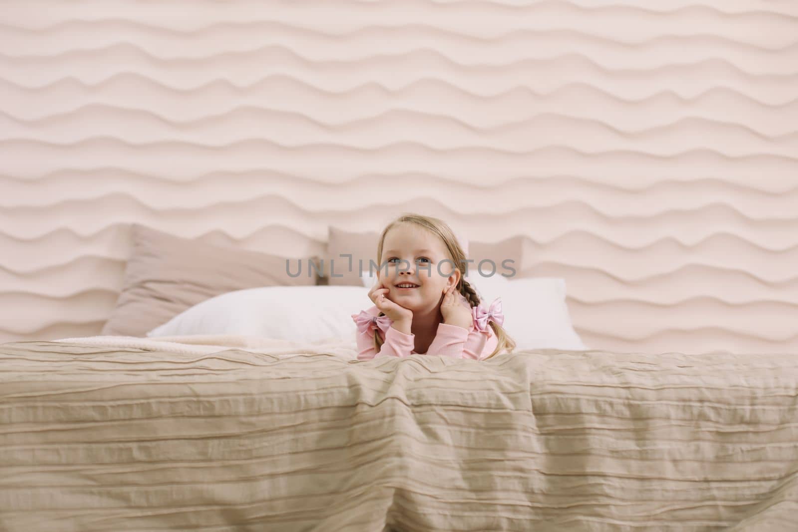 Morning of little girl in a comfortable bedroom. Happy child girl having fun and plays in bed.