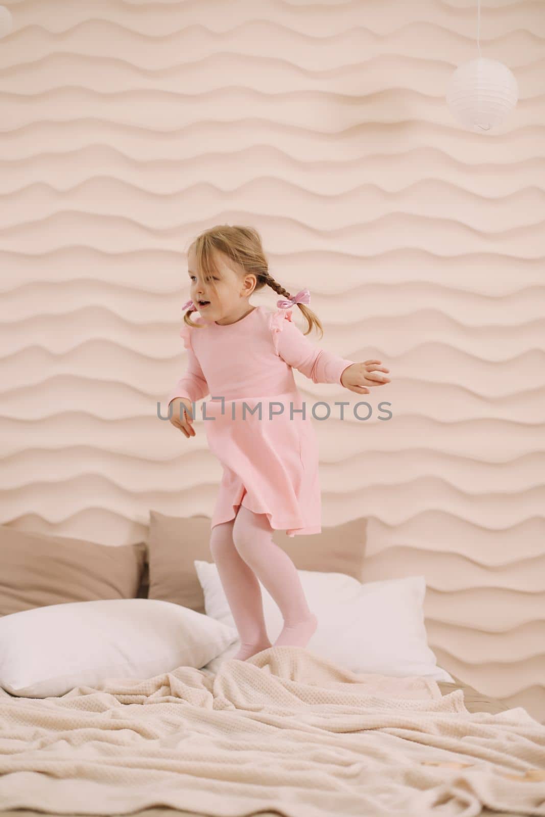 Morning of little girl in a comfortable bedroom. Happy child girl having fun and plays in bed.