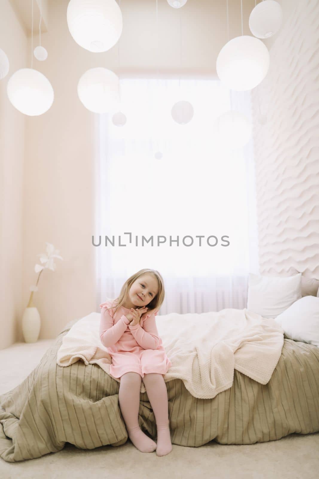 Morning of little girl in a comfortable bedroom. Happy child girl having fun and plays in bed by paralisart
