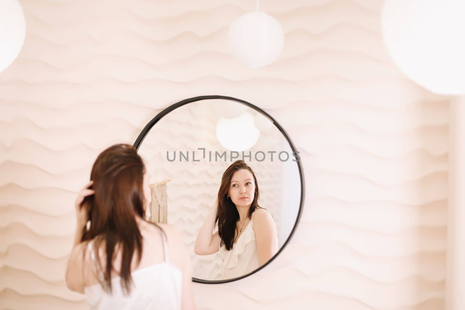 Portrait of calm pretty girl. Portrait of the woman reflected in mirror in a cozy light room in the morning