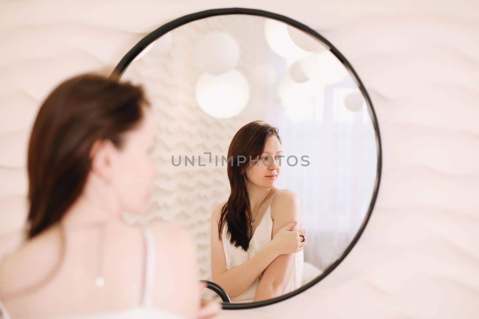 Portrait of calm pretty girl. Portrait of the woman reflected in mirror in a cozy light room in the morning