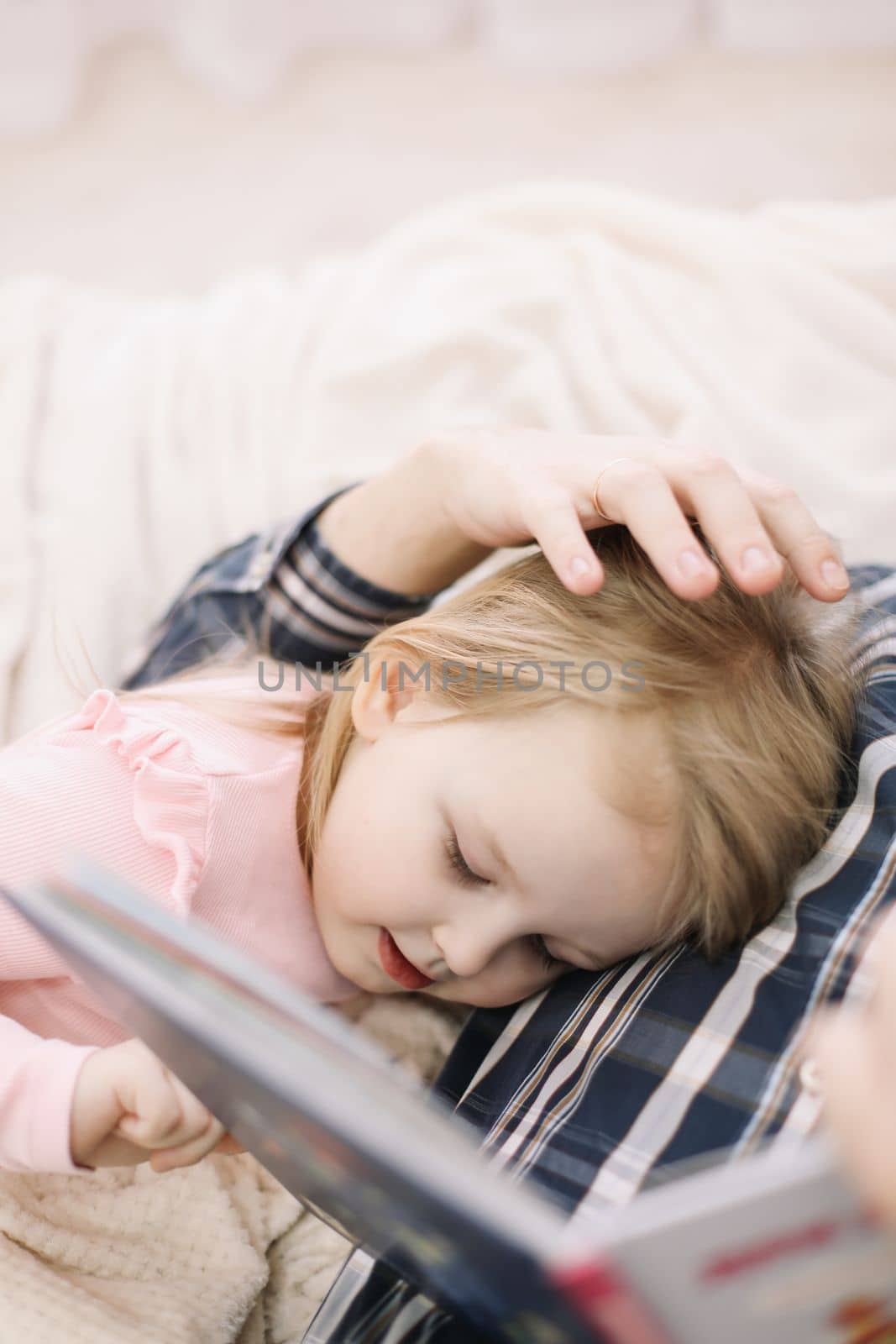 Father and little daughter spending weekend together at home, reading book in bed