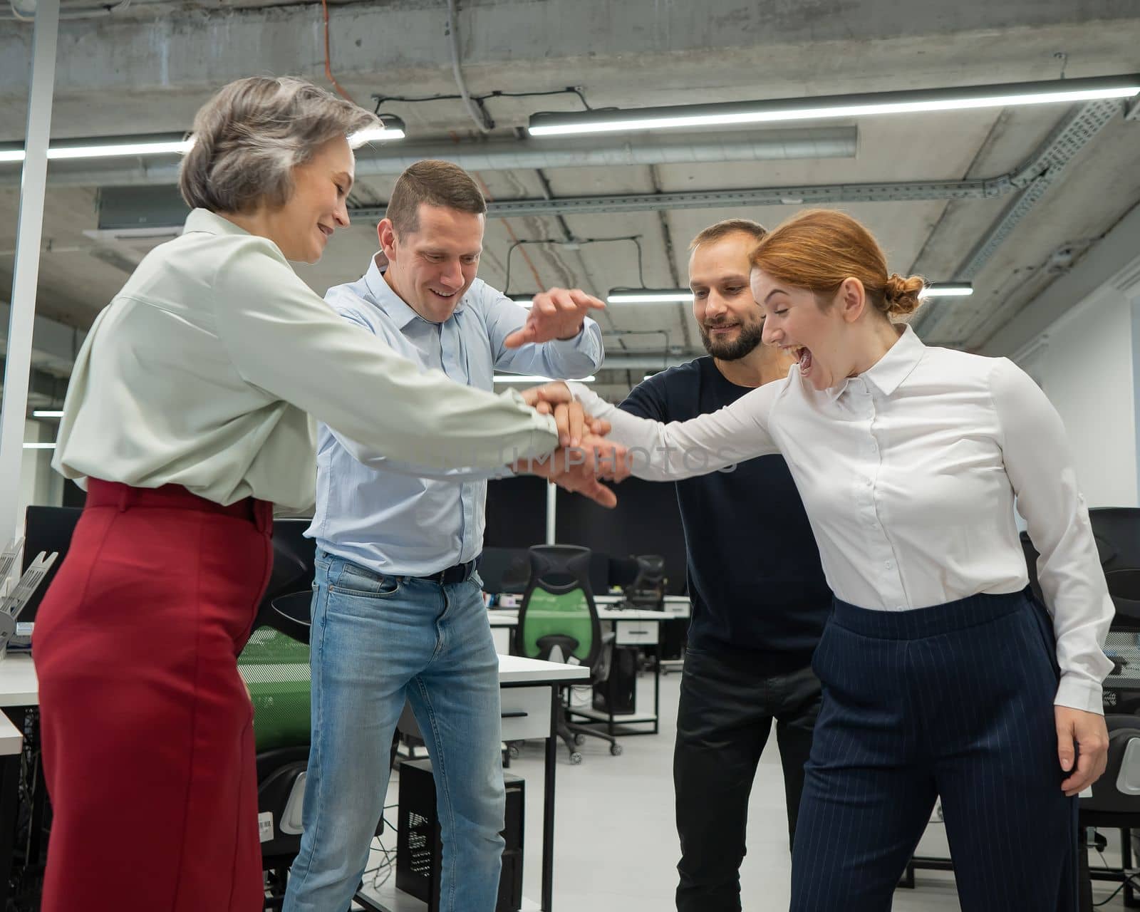 Four colleagues give the low five in the office