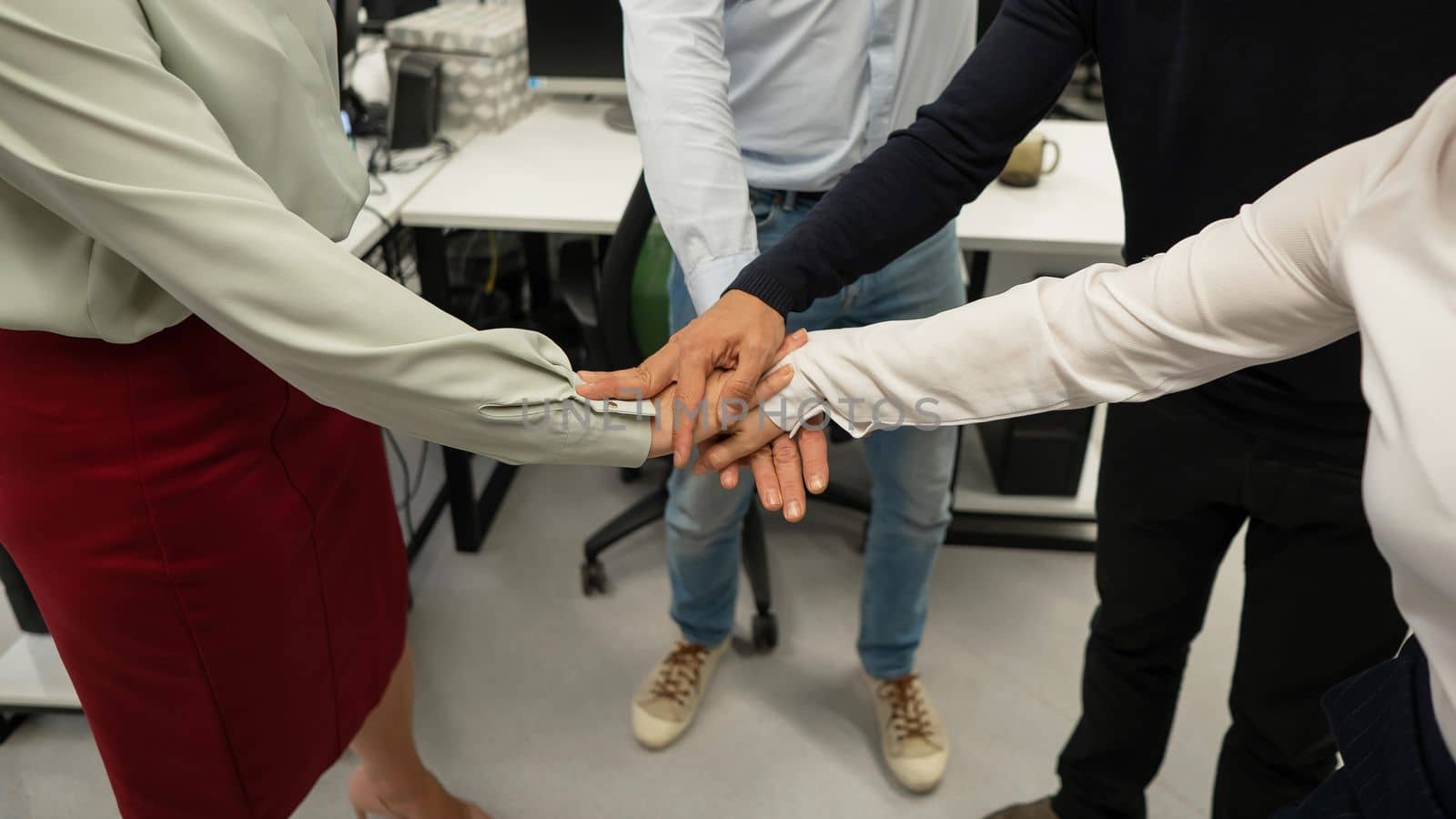 Four colleagues give the low five in the office. Close-up of the hands of office workers