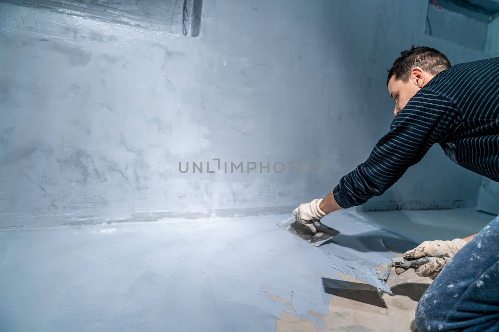 spread the insulation on the concrete floor using a trowel by Edophoto