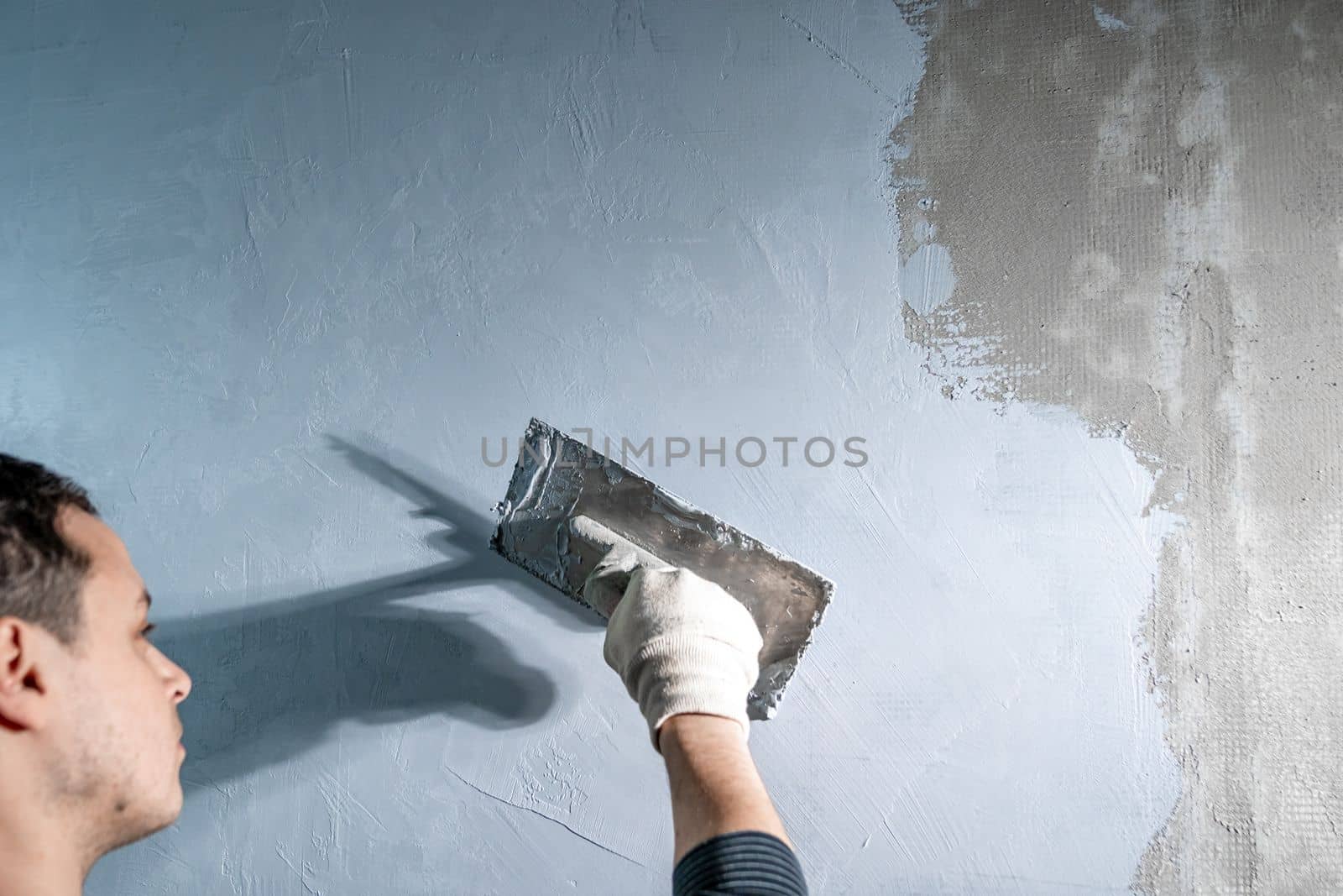 man applies insulation to a bathroom wall with trowel by Edophoto