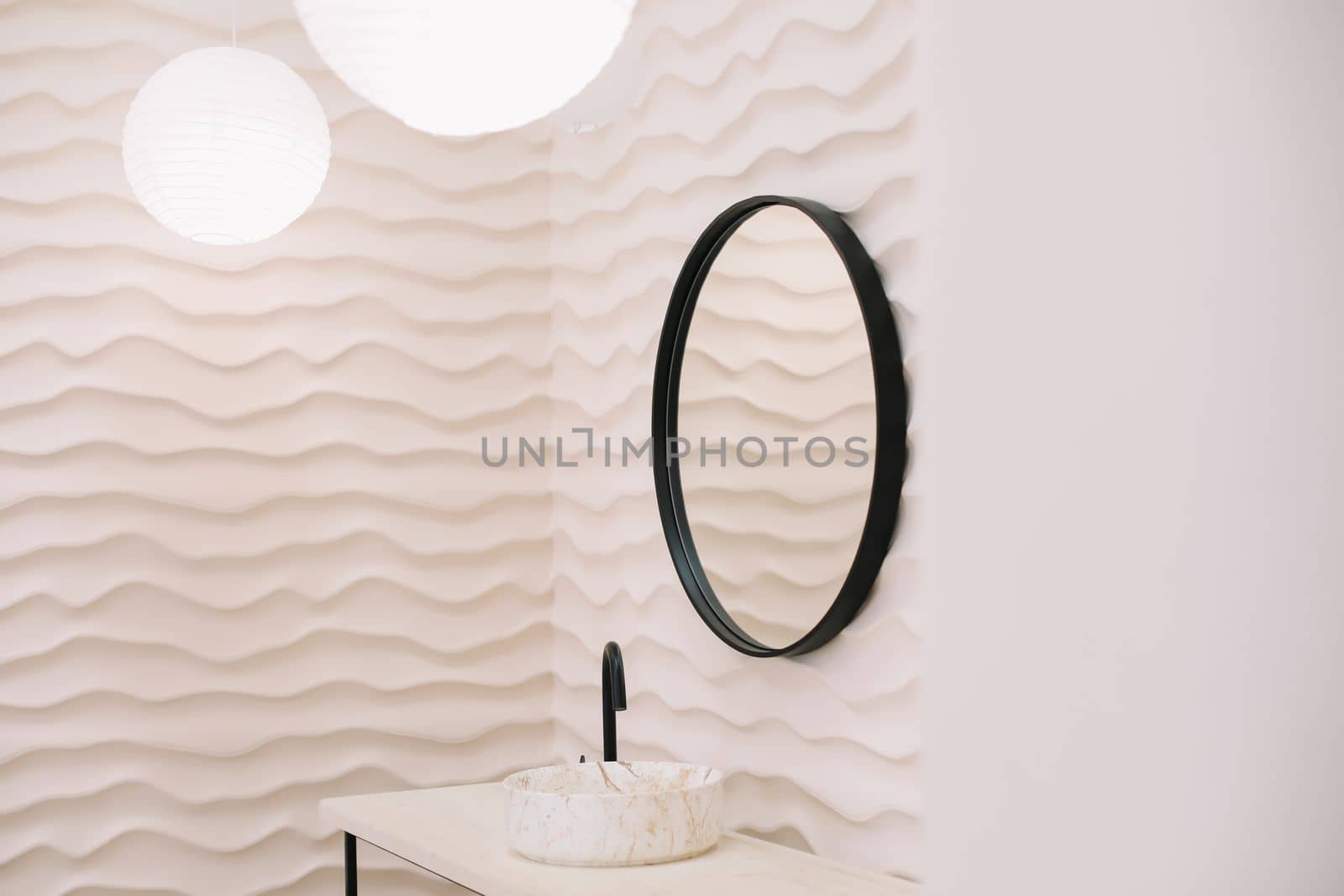 Modern interior with stylish round mirror by beige wall in a cozy room, copy space, elegant accessories in stylish home decor.