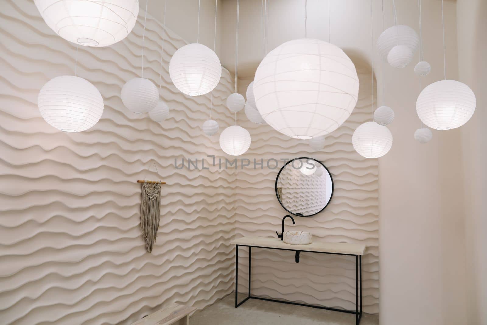 Modern interior with stylish round mirror by beige wall in a cozy room, copy space, elegant accessories in stylish home decor.