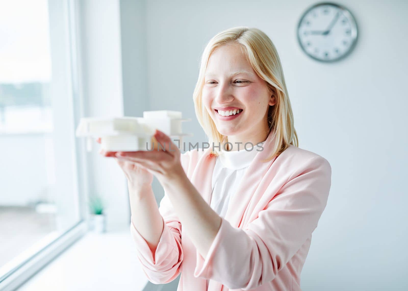 portrait of a young business woman holding a modern house model in the office