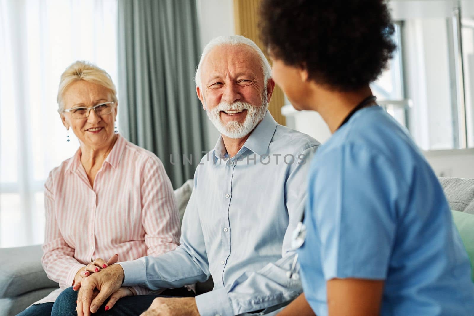 Doctor or nurse caregiver with senior couple at home or nursing home