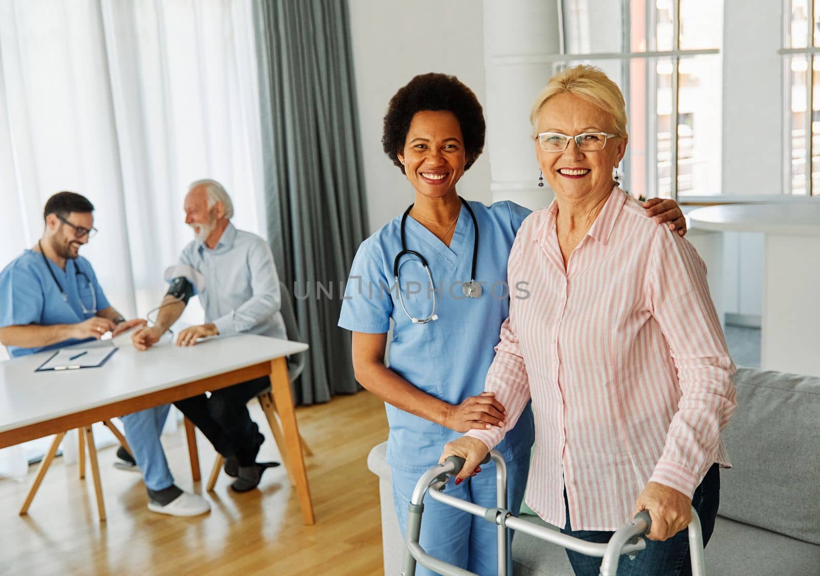Doctor or nurse caregiver with senior woman using walker assistanece at home or nursing home