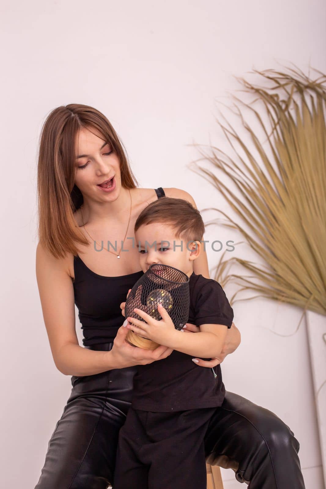A happy mother with a little boy, in black clothes, play. Vertical . Copy space