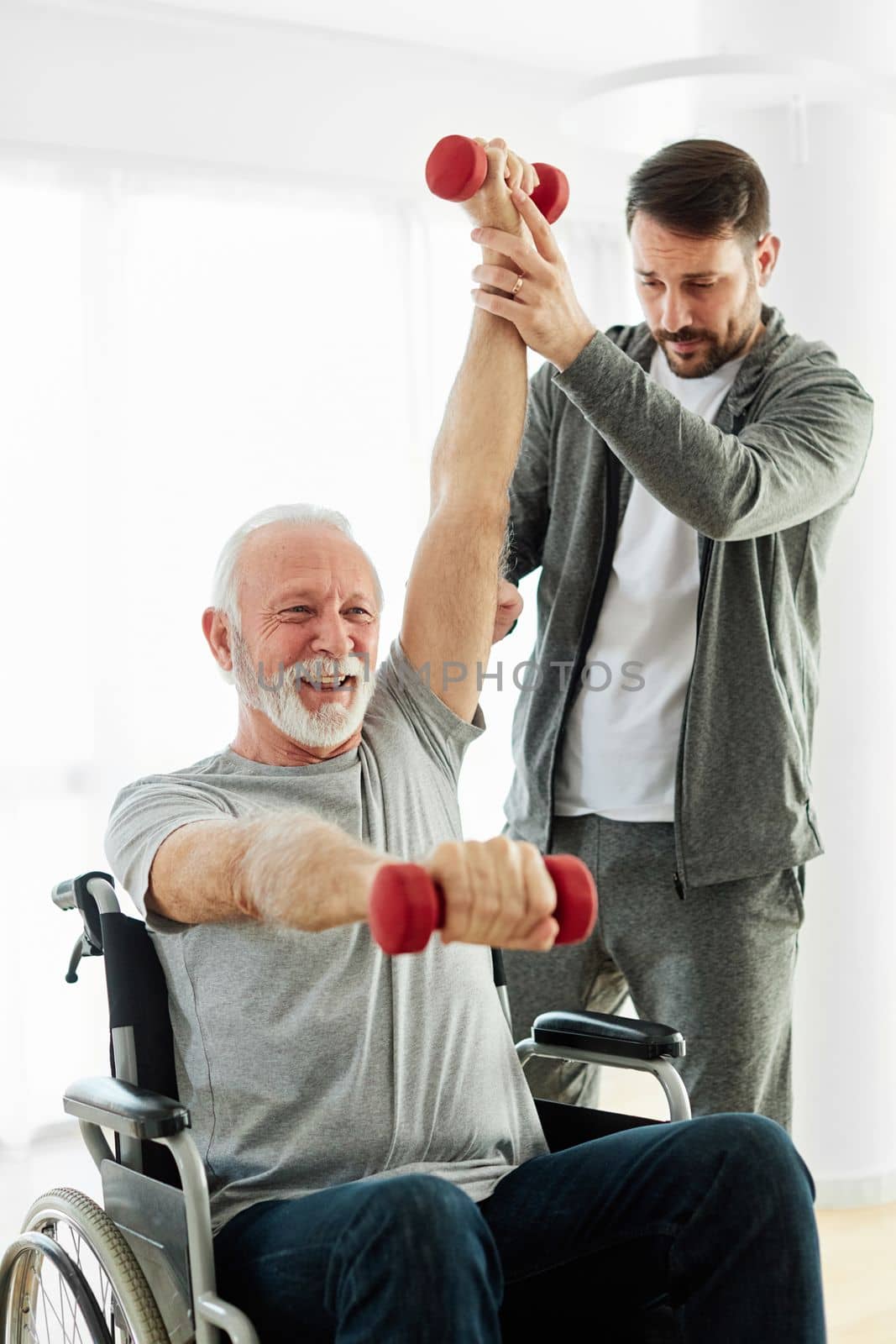 Doctor or nurse ot physiotherapist caregiver exercise with senior man at clinic or nursing home