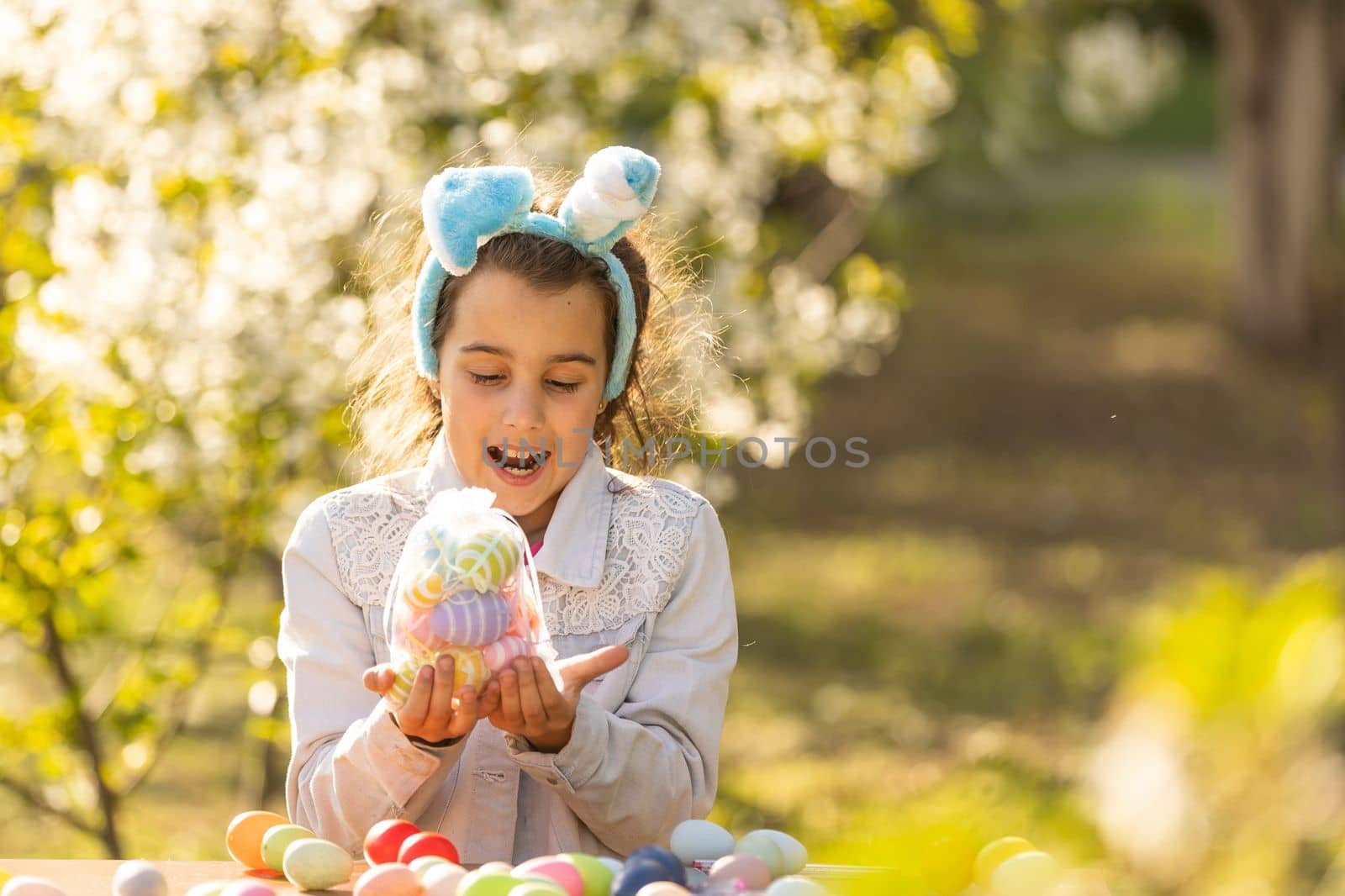 teenage girl paints easter eggs in the garden