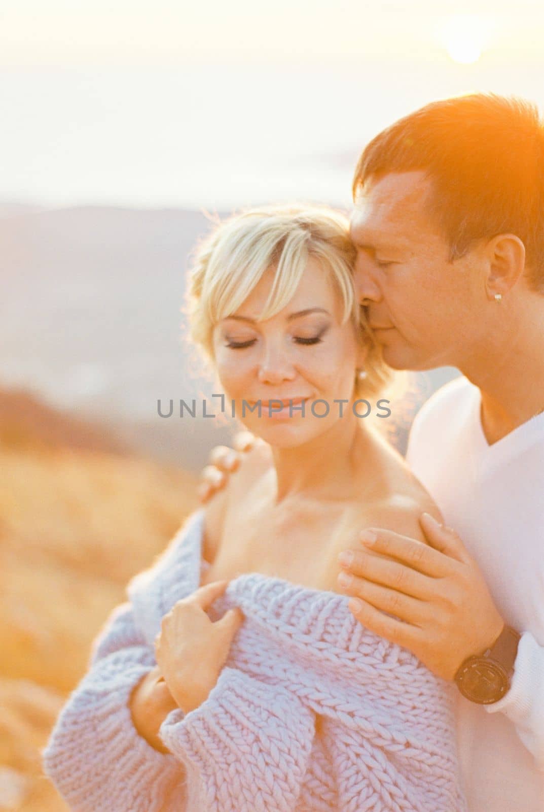 Man hugs a woman from behind and kisses her temple. High quality photo