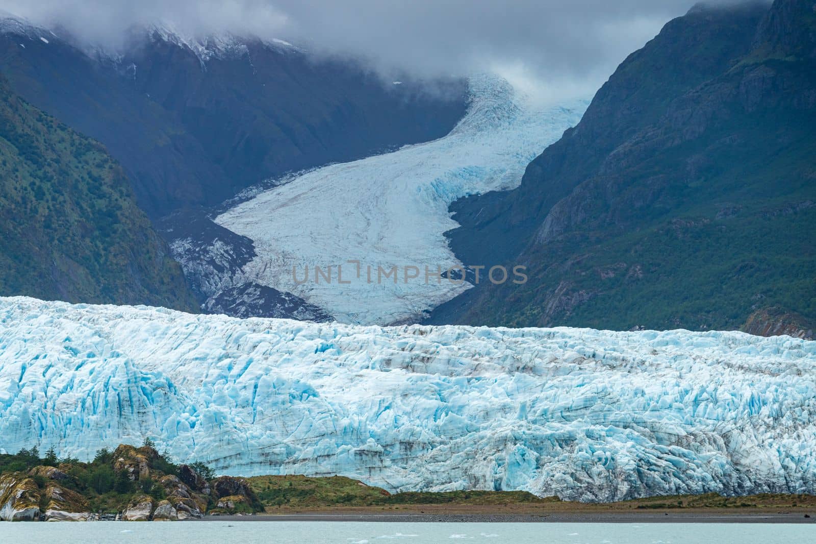 Milky light blue ocean by Amalia glacier with detail of the fissures and rocks in its path