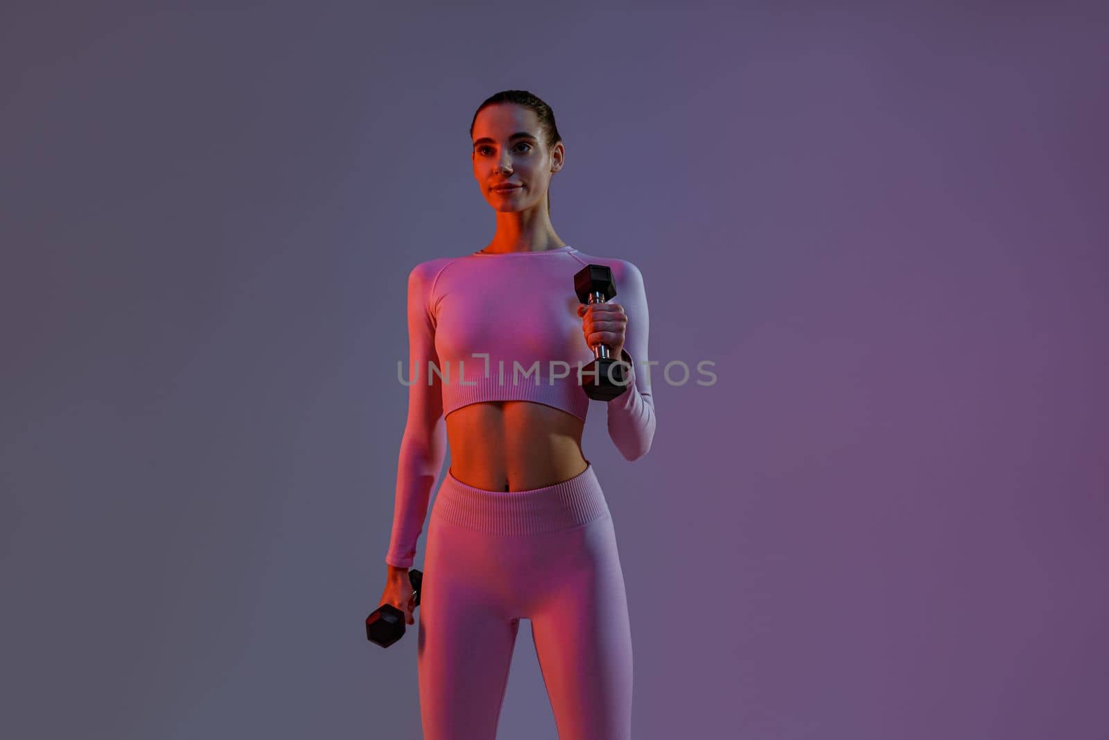 Woman doing exercises with dumbbells on studio background . Sport and healthy lifestyle