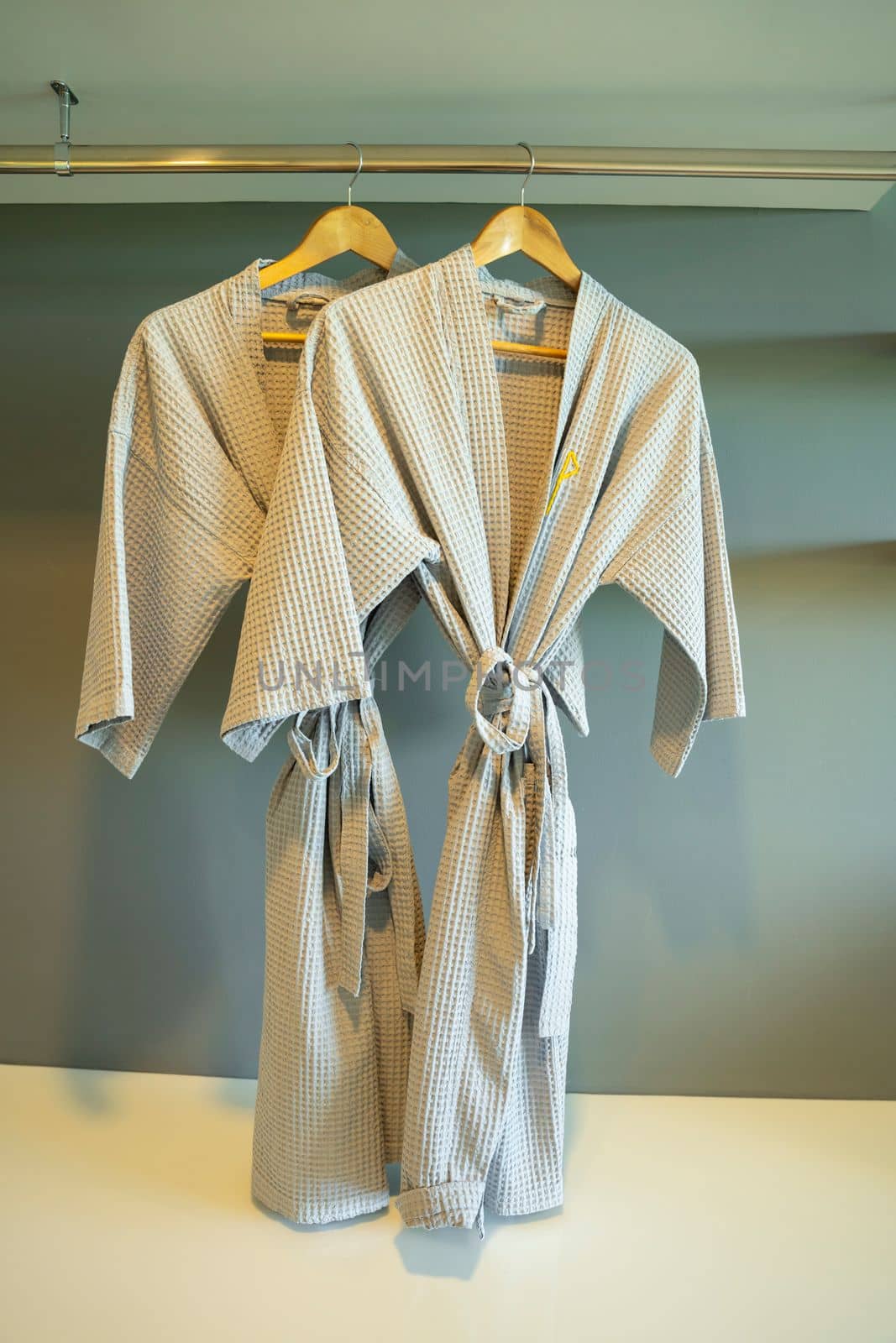 The Grey colored bathrobe on the hanger in the room at hotel. by Gamjai