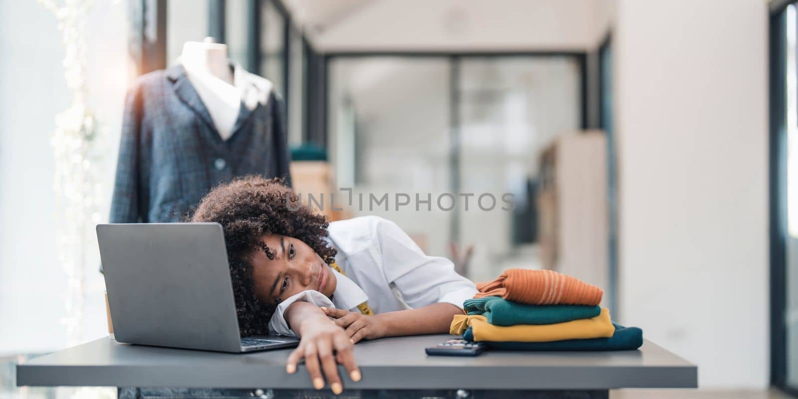 a Asian woman, a stylish fashion designer, thinking of problem to working, tried to new project, while a young businesswoman tries to recover after a long day's work in a clothing store. by wichayada