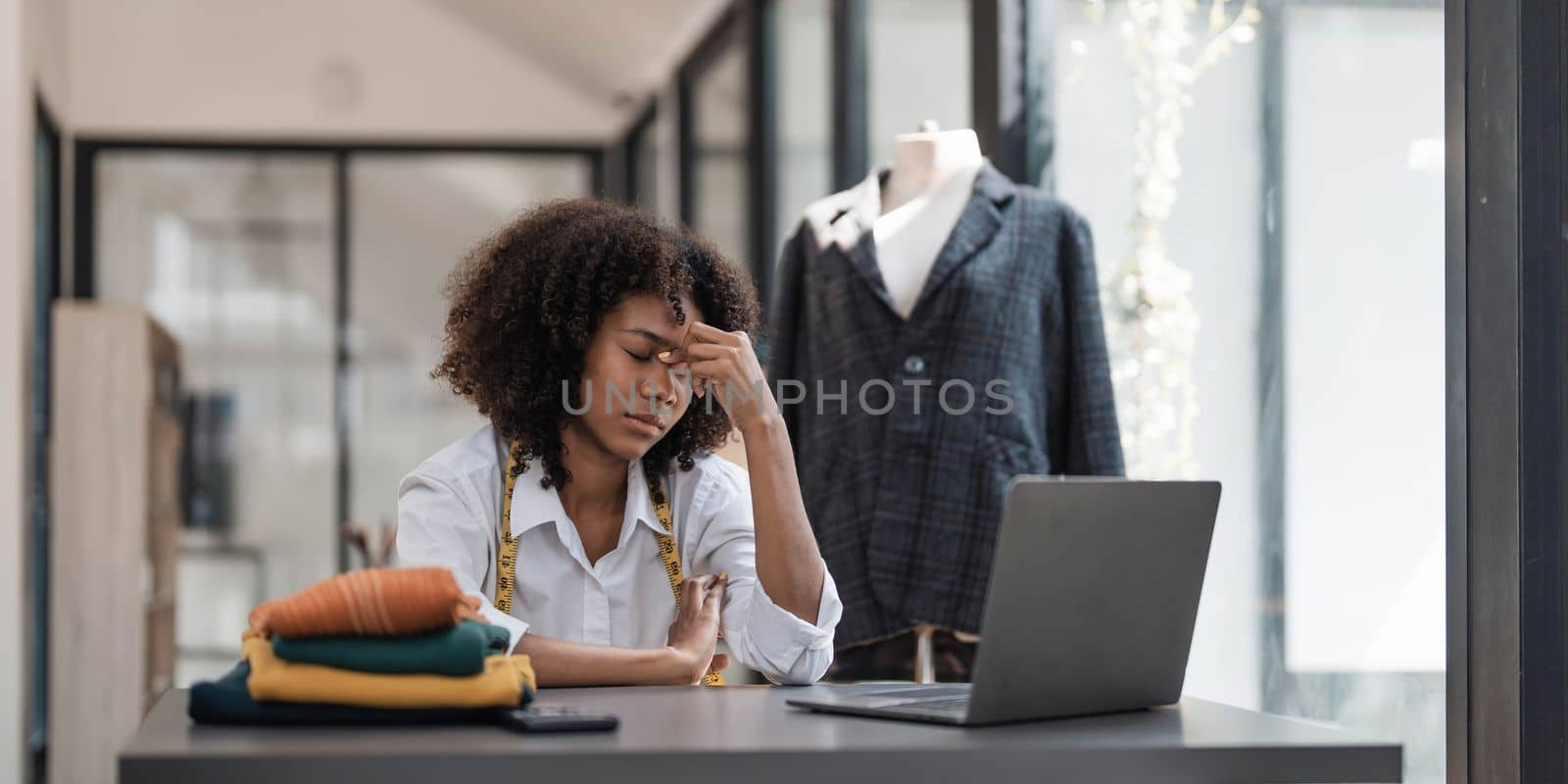 a Asian woman, a stylish fashion designer, thinking of problem to working, tried to new project, while a young businesswoman tries to recover after a long day's work in a clothing store