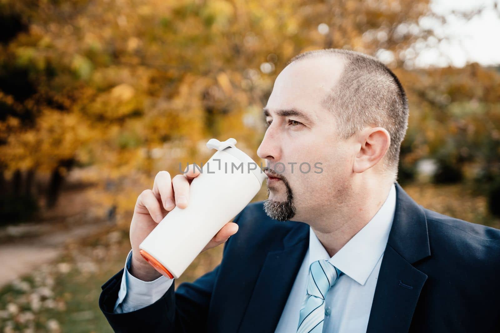 Mature entrepreneur drink coffee in autumn park. Senior executive rest in city park.