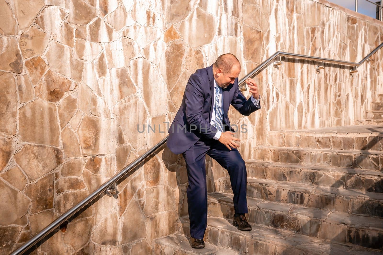 Portrait of a senior professional man in a suit with various problems. A middle-aged businessman with a briefcase descends the stairs.