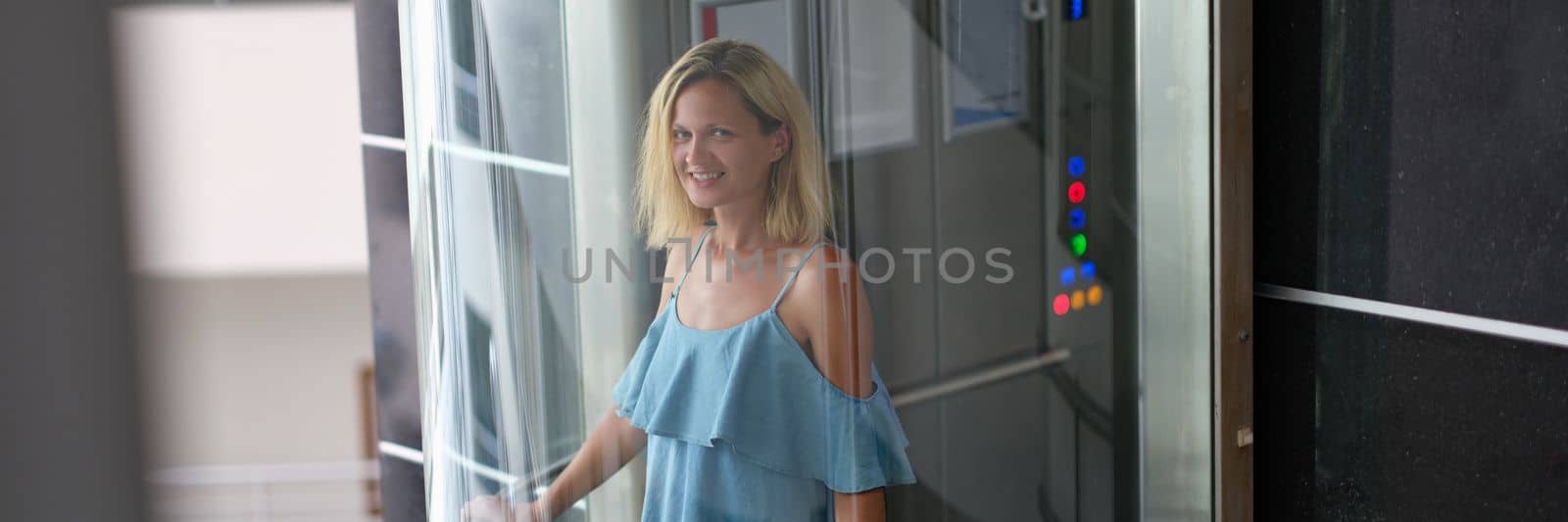 Beautiful smiling woman in transparent glass elevator. Stylish modern elevators in hotels and business centers concept