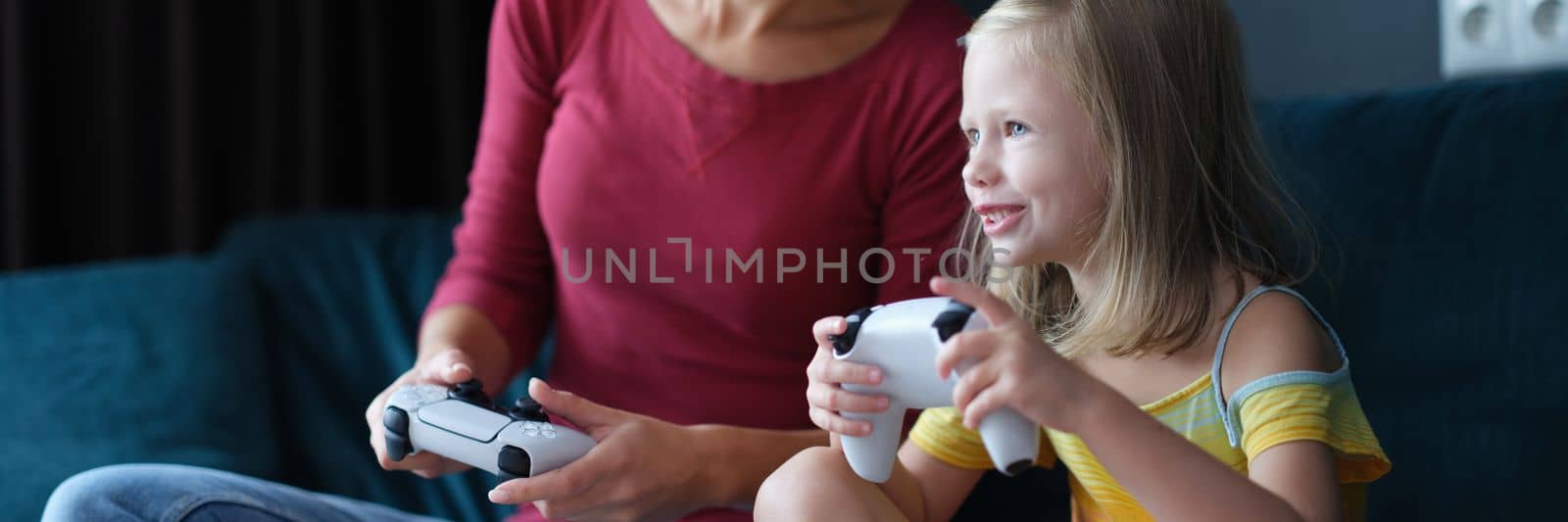 Mother and baby girl playing video games. Happy family together and having fun at home playing online games