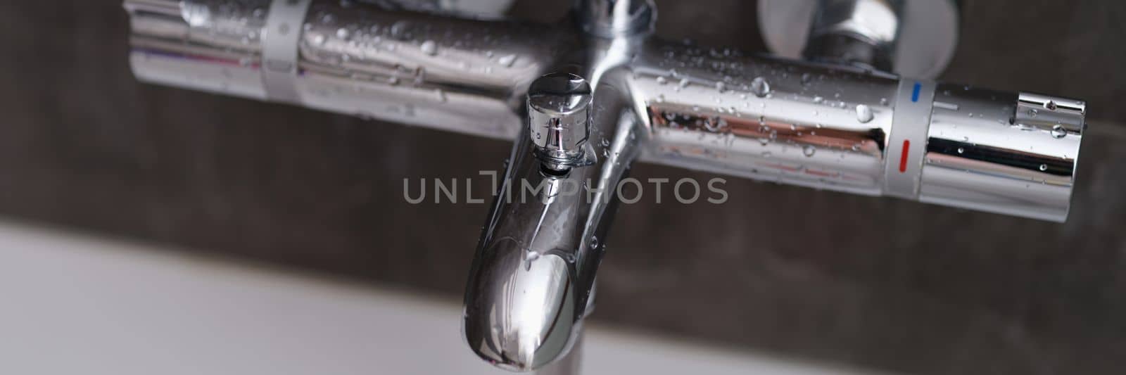 Chrome faucets on white ceramic bathtub in bathroom. Water drops on the faucet in bathroom concept