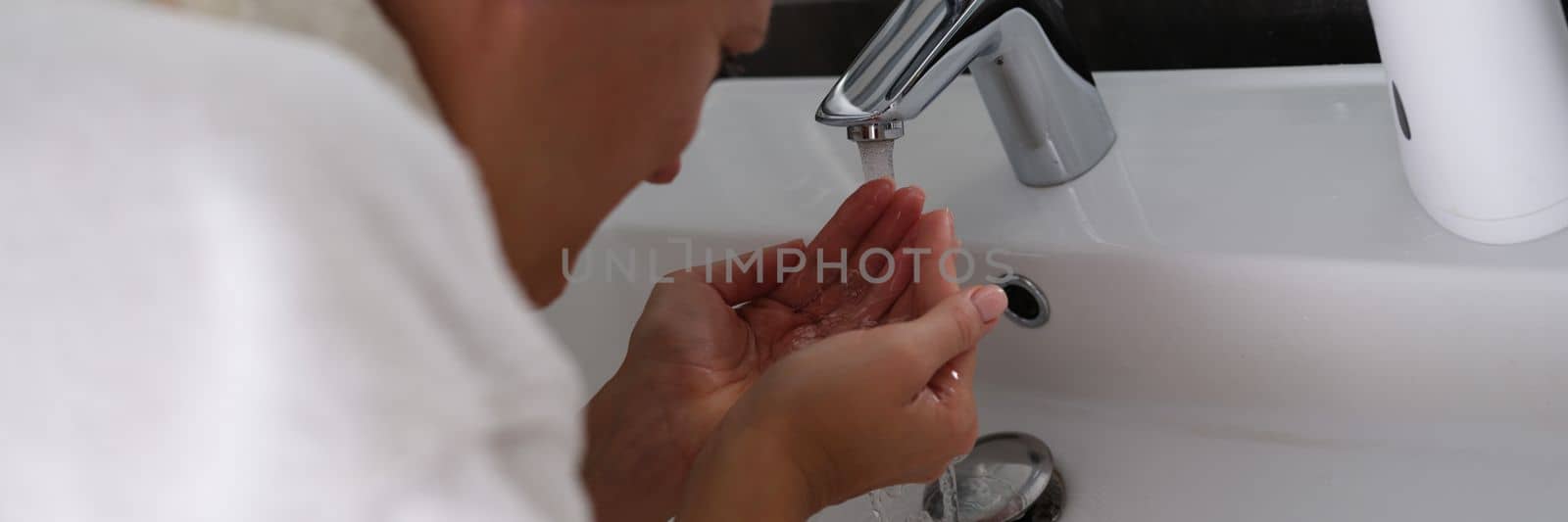 Young woman washes face with clean water in bathroom. Facial skin care concept