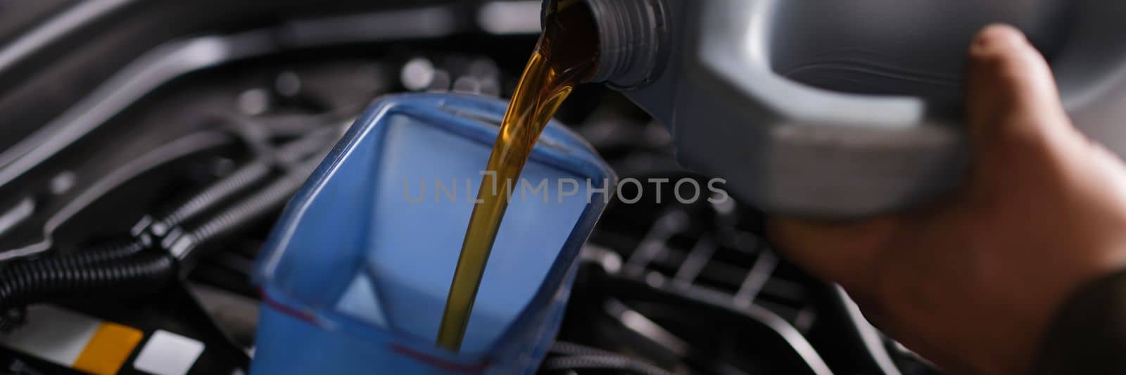 Auto mechanic replaces and pours fresh oil into engine at service station. Engine maintenance concept