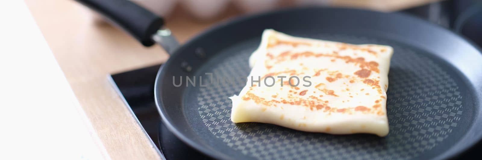 Folded pancake in frying pan against background of chicken eggs in kitchen by kuprevich