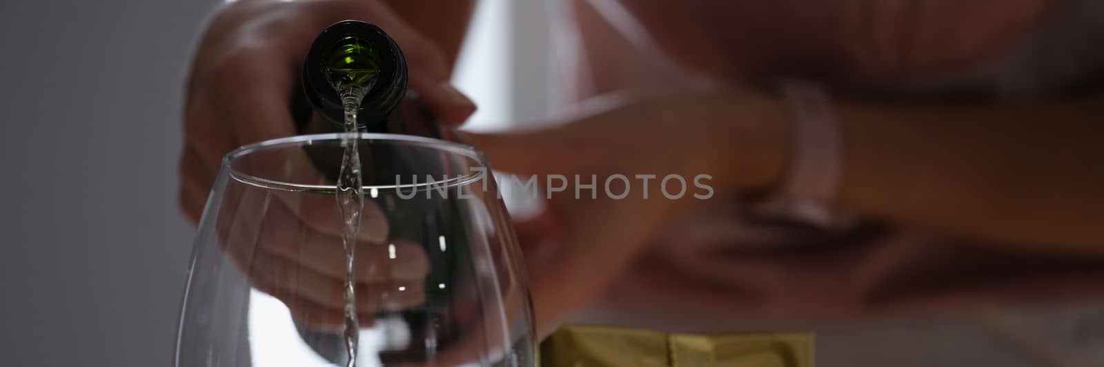 Woman pours white wine or champagne into glass and romantic dinner with gift by kuprevich